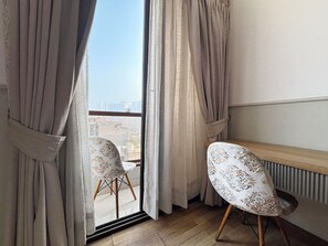 A room with a large window, two patterned chairs, and a radiator.