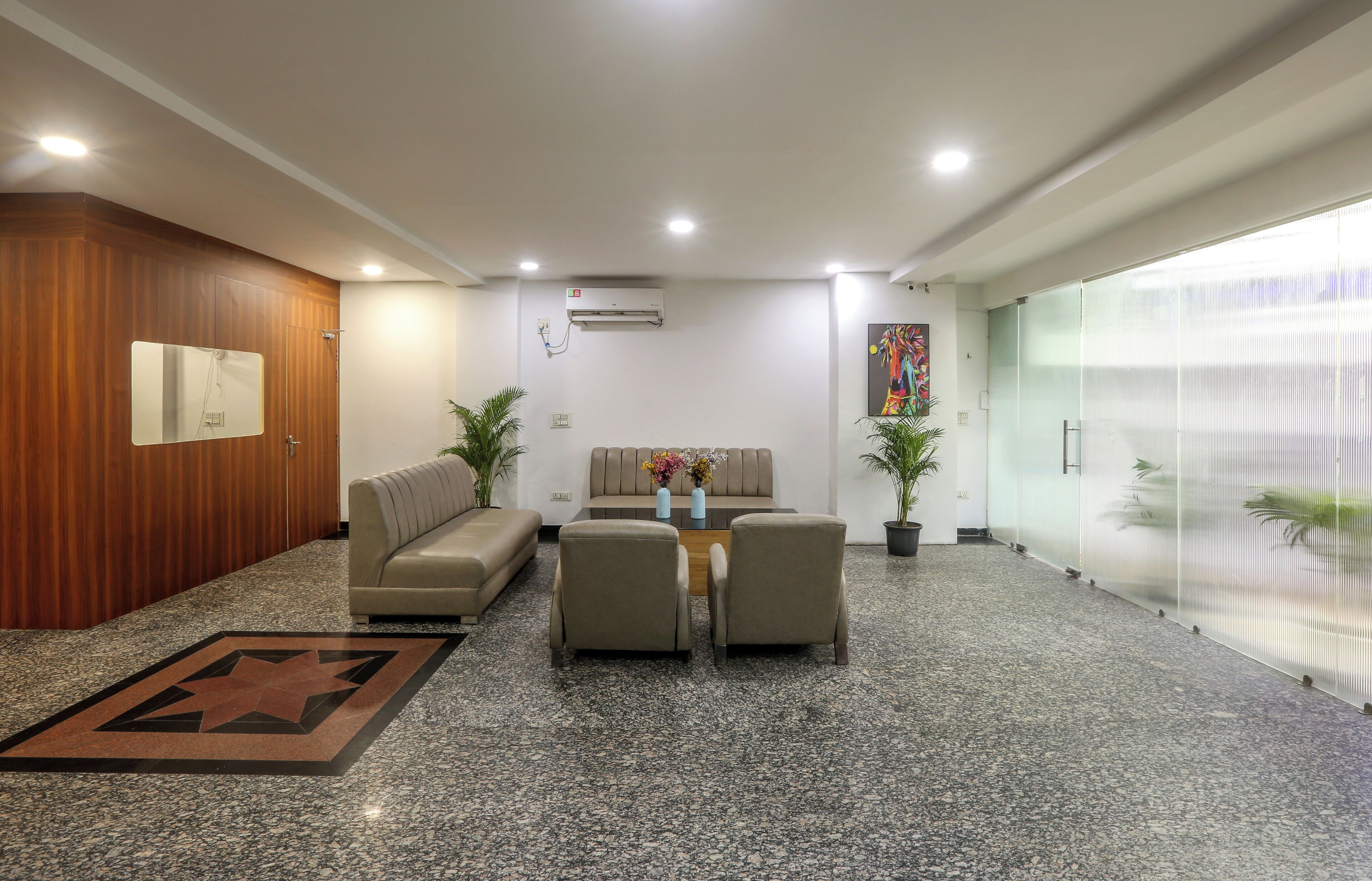 A modern waiting area with a sofa, two armchairs, a coffee table, and a decorative rug.