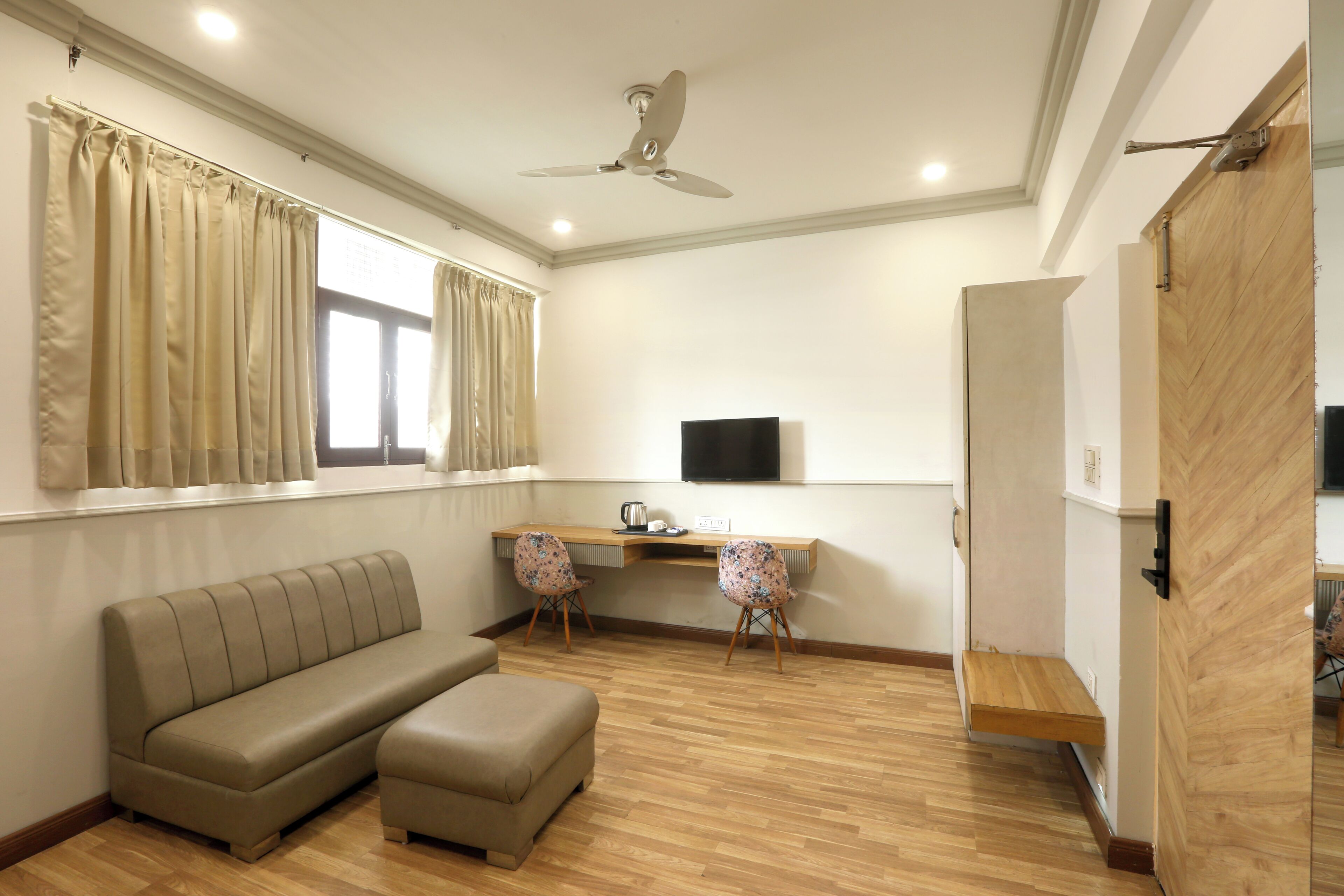 Un salon moderne comprenant un canapé, deux fauteuils, un téléviseur et un ventilateur de plafond.