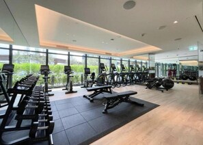 Ein modernes Fitnessstudio mit verschiedenen Trainingsgeräten, großen Fenstern und einer hellen, großzügigen Gestaltung.