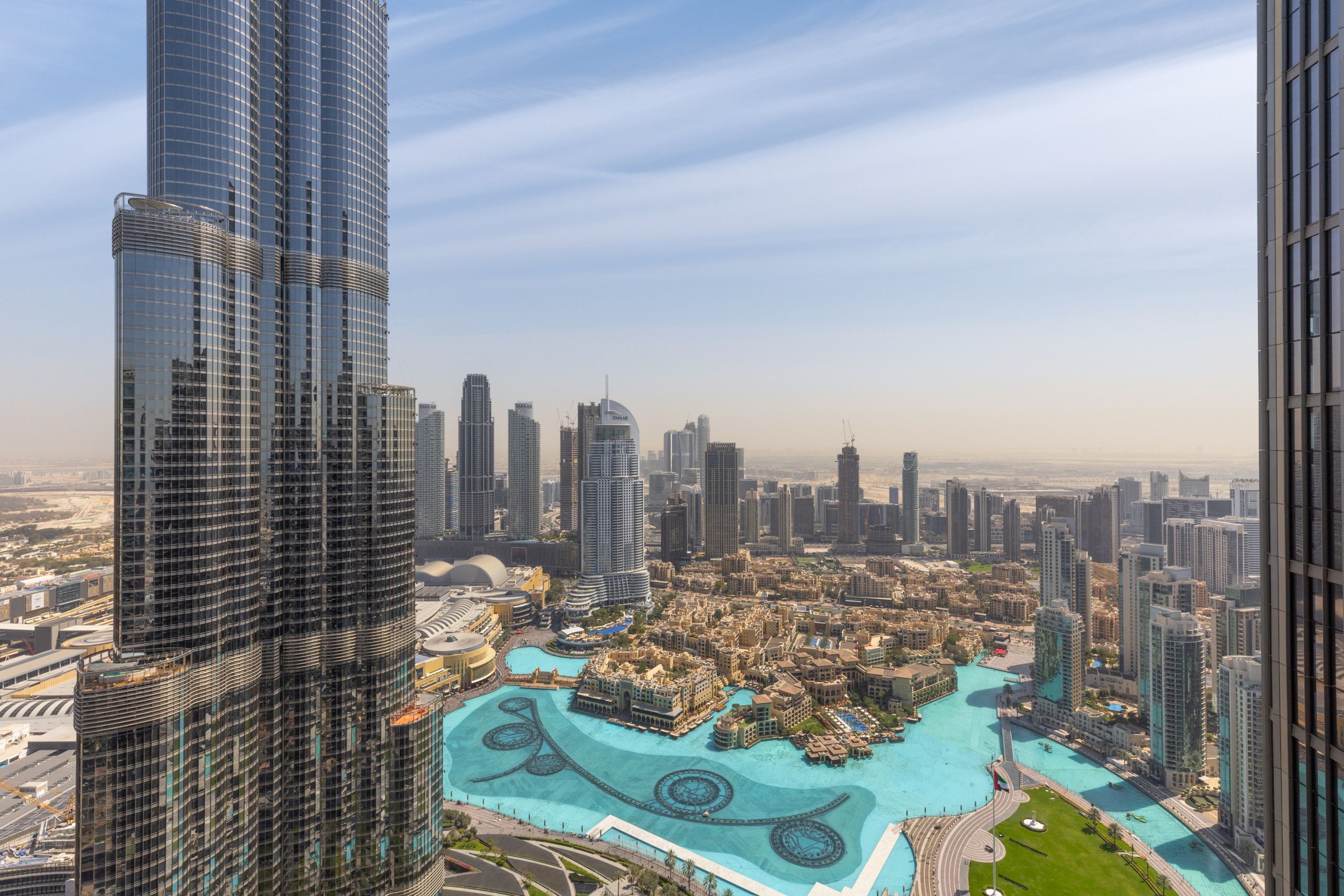 A high-rise building with a modern glass facade, a large central courtyard with water features, and surrounding high-rise buildings.