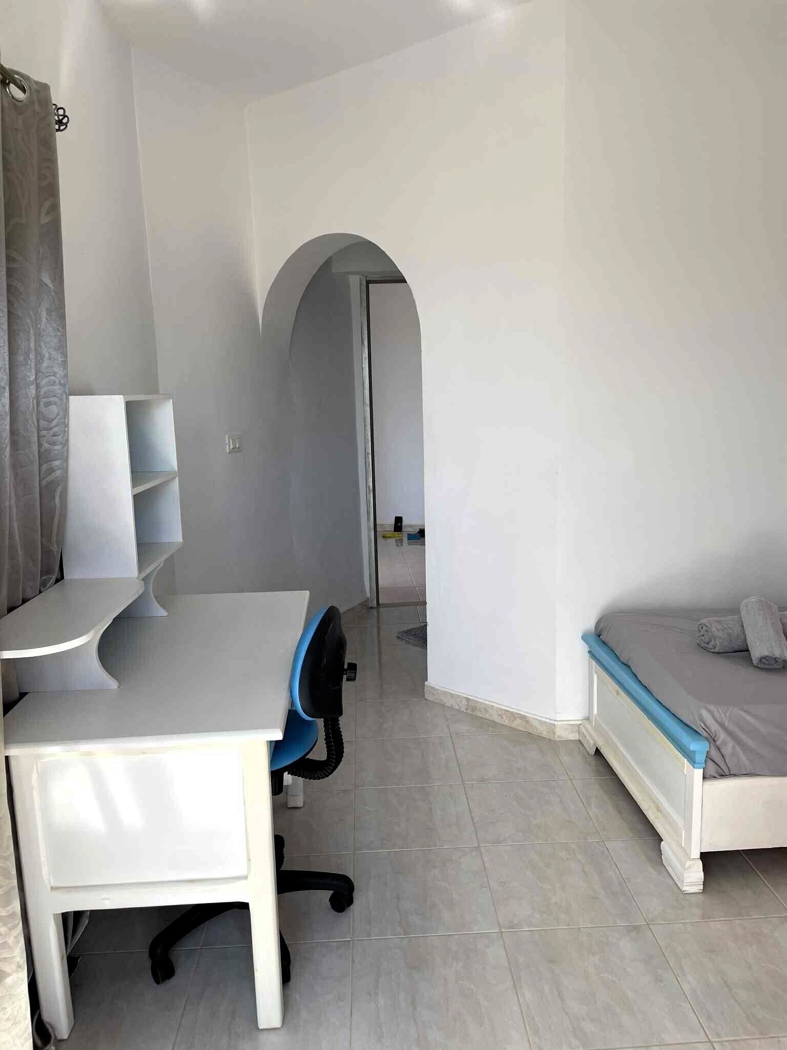 Habitació amb escriptori, cadira i llit amb capçalera.