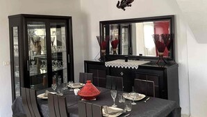 A dining area with a black table, dark chairs, and a decorative red pot.