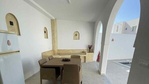 A compact kitchen with a dining area, a refrigerator, and a bench.