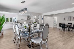 A modern kitchen with white cabinets, stainless steel appliances, and a dining area with a glass table and chairs.