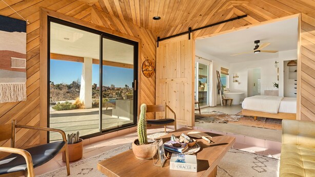 Um interior moderno com painéis de madeira, um cacto sobre uma mesa e vista para o deserto.