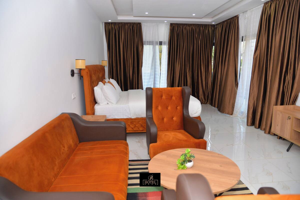 Ein modernes Hotelzimmer mit Sofa, Sesseln und einem kleinen Tisch mit einer Pflanze.