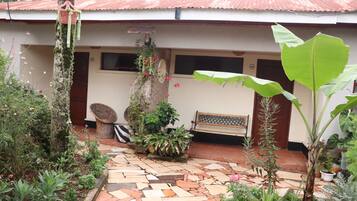 A courtyard with a tiled floor, a bench, and various potted plants.