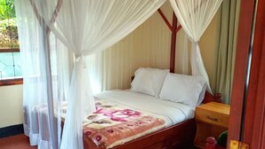 A bed with a canopy, a bedside table, and a patterned rug. - Marangu Summit Lodge (Marangu)