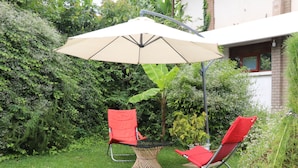 An outdoor seating area with a table and two chairs, an umbrella, and a small decorative plant. - Marangu Summit Lodge (Marangu)