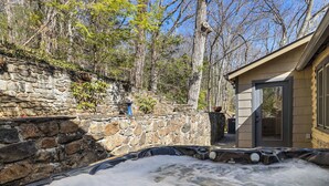 A hot tub area with stone walls and a wooden cabin. - Hottub/Arcade/Historic Cabin/Mins to AVL & WVL (Weaverville)