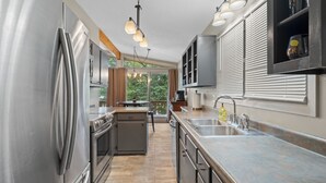 Een moderne keuken met roestvrijstalen apparatuur, een groot eiland met een spoelbak en uitzicht op de omgeving.