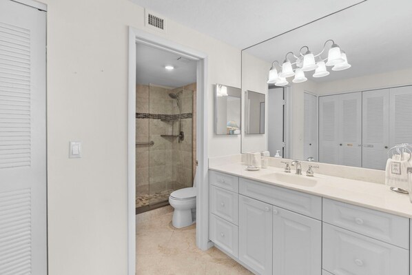A modern bathroom with a walk-in shower, a large mirror, and a vanity with a sink and multiple drawers. - Sun, Sand, and Serenity I Beachfront on Marco Island (Marco Island)