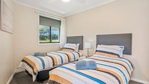 A hotel room with two beds, a window with a view, and a lamp on the nightstand.