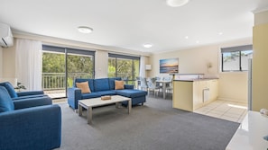 A modern living room with a sofa, coffee table, and dining area.