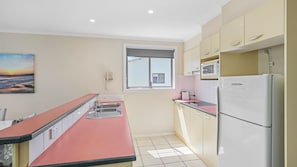 A compact kitchen with a refrigerator, microwave, and sink.
