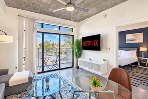 A modern hotel room with a large balcony, a flat-screen TV, a sofa, a glass coffee table, and a bed. - Luxury Stay at DT PHX Balcony,Pool,Gym,Parking,WD (Phoenix)