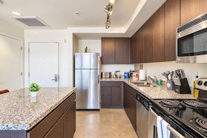 Una cocina moderna con encimeras de granito, electrodomésticos de acero inoxidable y armarios de madera oscura.