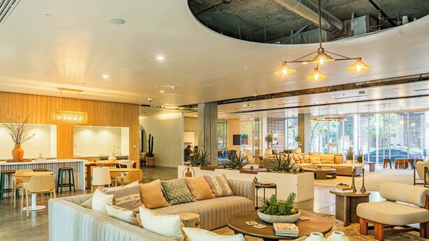 A spacious lobby with a large seating area, a kitchen in the background, and large windows providing natural light. - Luxury Stay at DT PHX|Balcony,Pool,Gym,Parking,W/D (Phoenix)