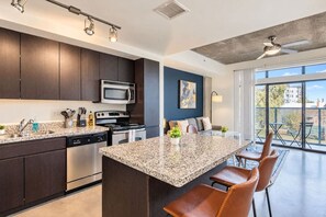 A modern kitchen with dark cabinetry, stainless appliances, and a granite countertop. - Luxury Stay at DT PHX Balcony,Pool,Gym,Parking,WD (Phoenix)