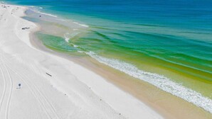 Une plage à l’eau d’un bleu limpide et au sable blanc.