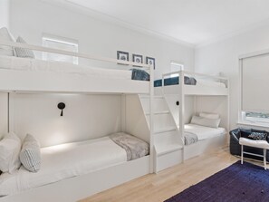 A bunk bed room with a desk and a window.