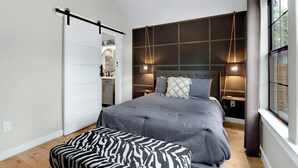 A bedroom with a bed, bedside lamps, a ceiling fan, and a window. - Little White House of Wimberley I River access (Wimberley)