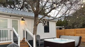 A backyard with a hot tub, wooden deck, and a small shed with a window. - Little White House of Wimberley I River access (Wimberley)