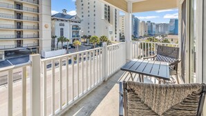 A balcony with a table and chairs, a view of the street, and a building with a sign. - Ocean View l 5BR l Pool l Sleeps 16 l Luxury Villa (north myrtle beach)