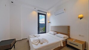 Une chambre d’hôtel avec un lit, une table de chevet et une vue sur la mer par la fenêtre.