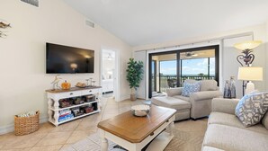 Een woonkamer met een televisie, bank, salontafel en een balkon met uitzicht.