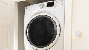 A stacked washer and dryer unit in a laundry room with a patterned tablecloth and a plastic container with items on it. - Sosuite | 2BR Apt w W/D, Newly renovated (Philadelphia)