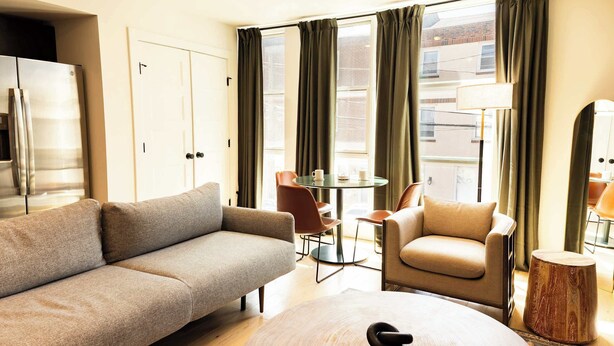 A modern living room with a sofa, armchair, round coffee table, and a small wooden side table. - Sosuite | 2BR Apt w W/D, Newly renovated (Philadelphia)
