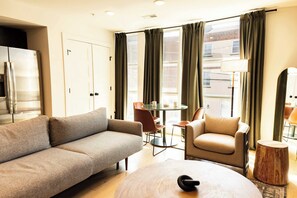 A modern living room with a sofa, armchair, round coffee table, and a small wooden side table. - Sosuite | 2BR Apt w W/D, Newly renovated (Philadelphia)