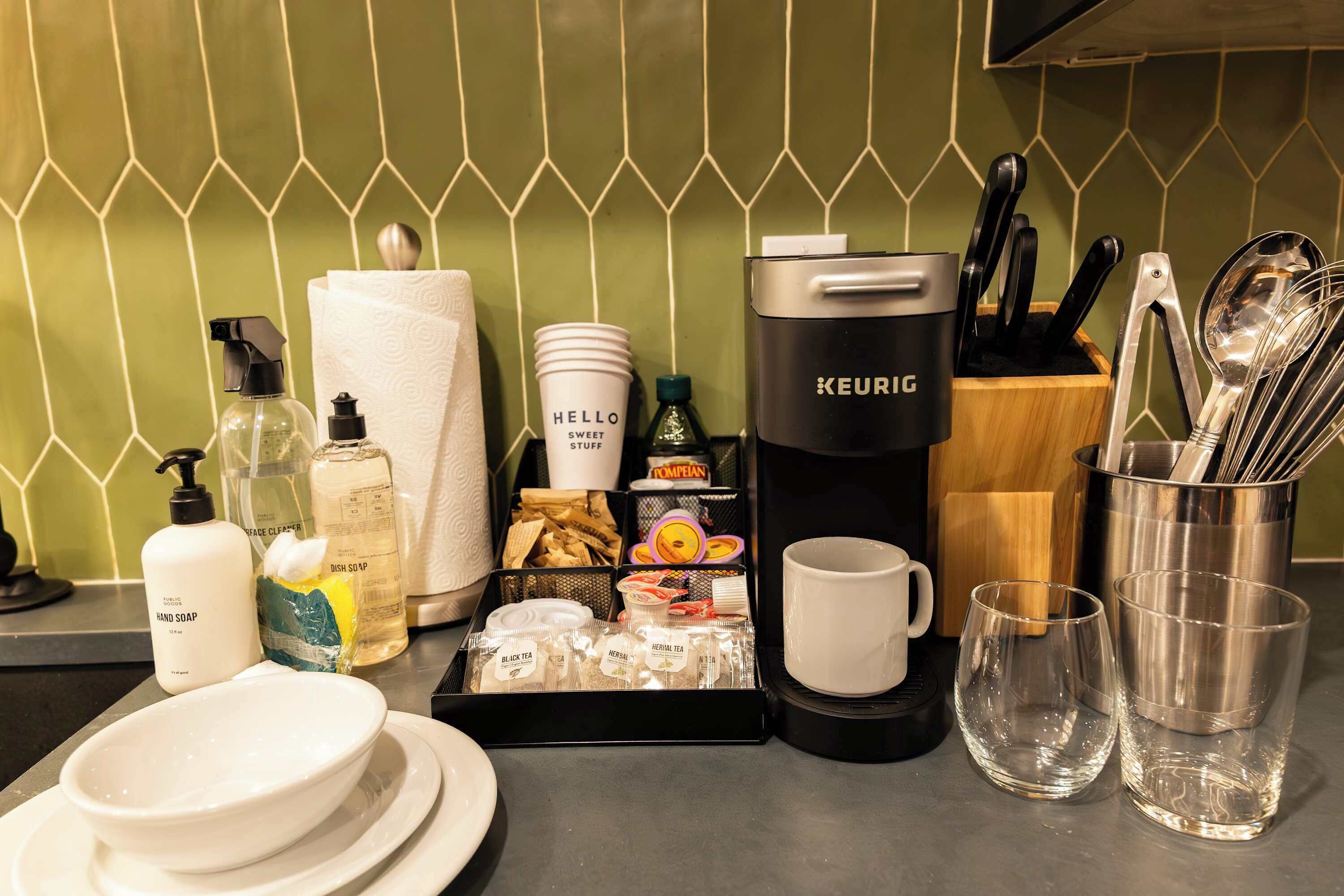 Uma bancada de cozinha com cafeteira, utensílios e diversos objetos de cozinha.