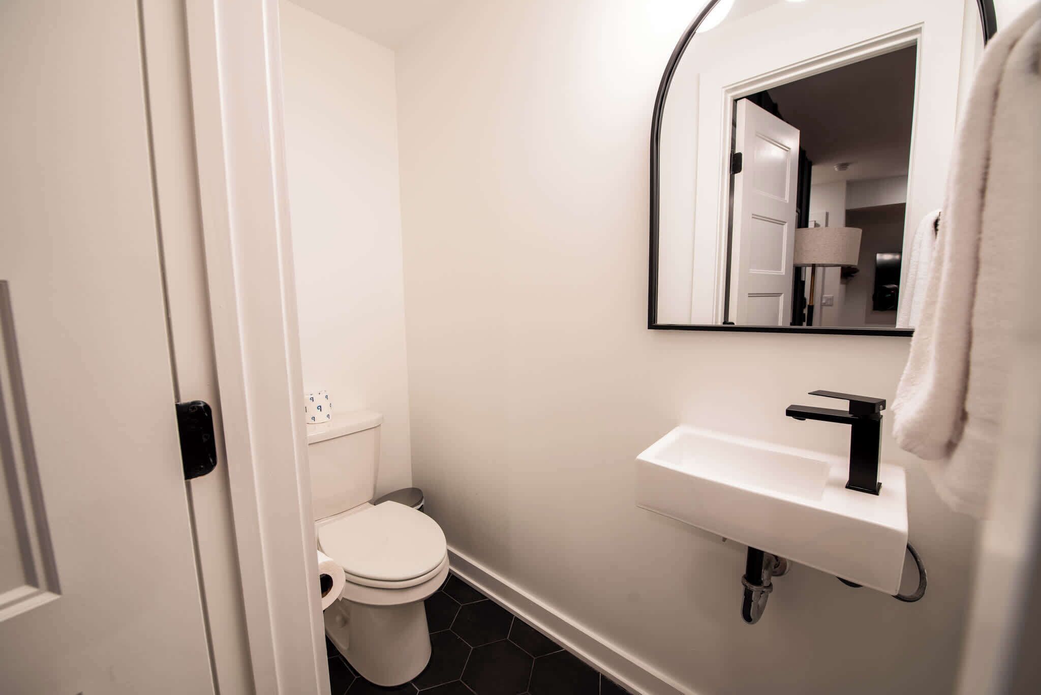 A modern bathroom with a toilet, sink, and mirror.