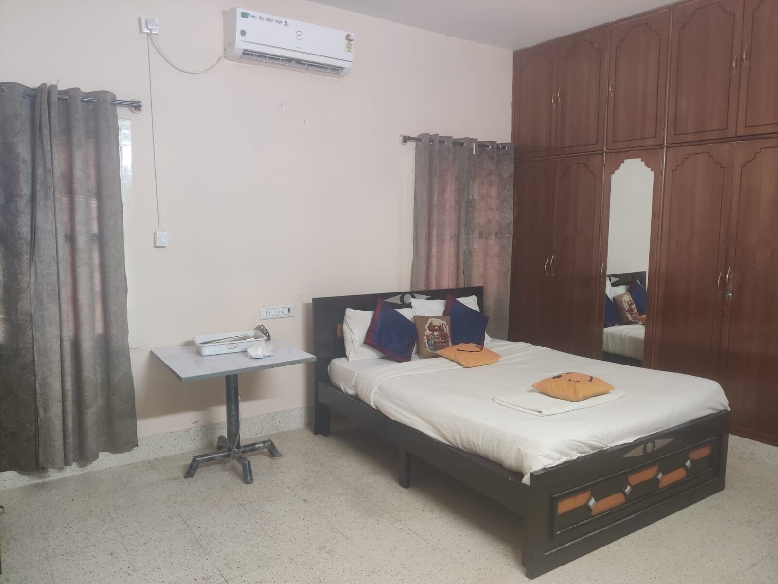 A bedroom with a bed, a bedside table, an air conditioning unit, and a wardrobe.