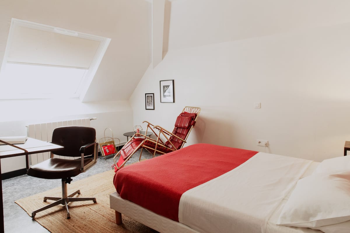 Ein Schlafzimmer mit Bett, Schreibtisch, Stuhl und Fenster.