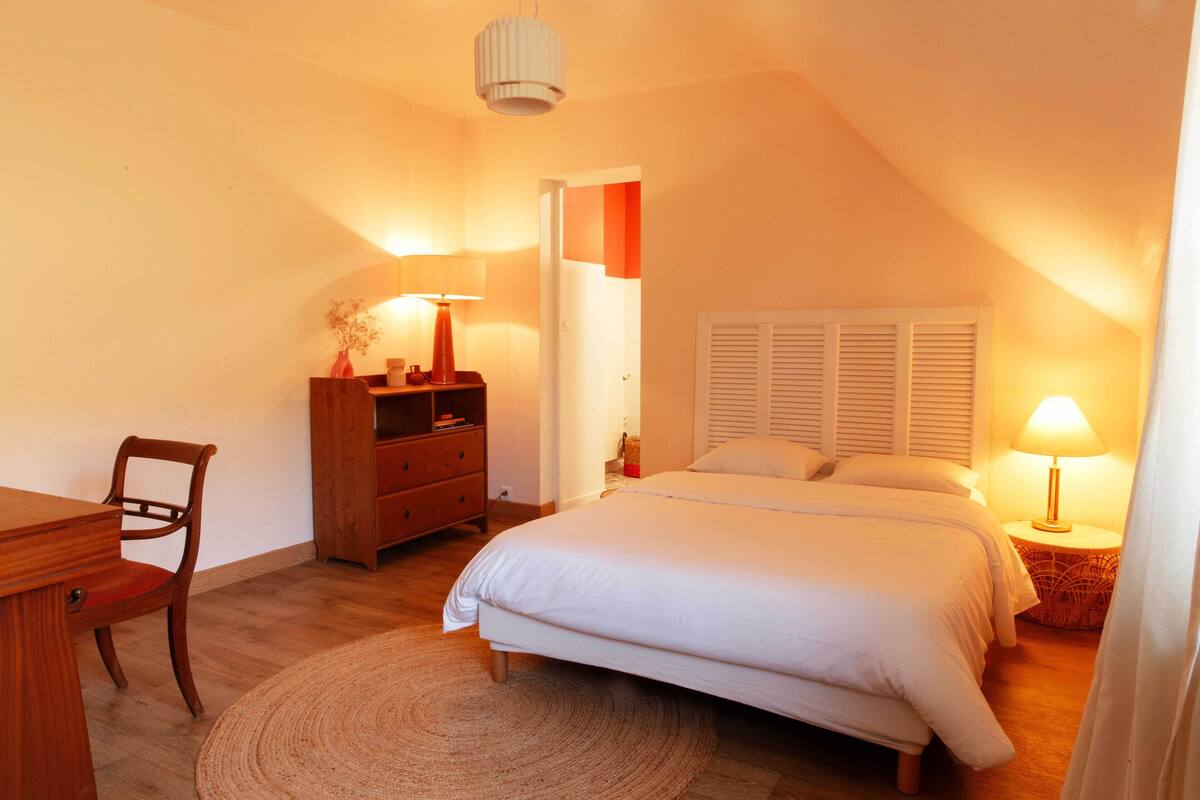 Ein Schlafzimmer mit Bett, Schreibtisch, Stuhl, Kommode und Lampe.