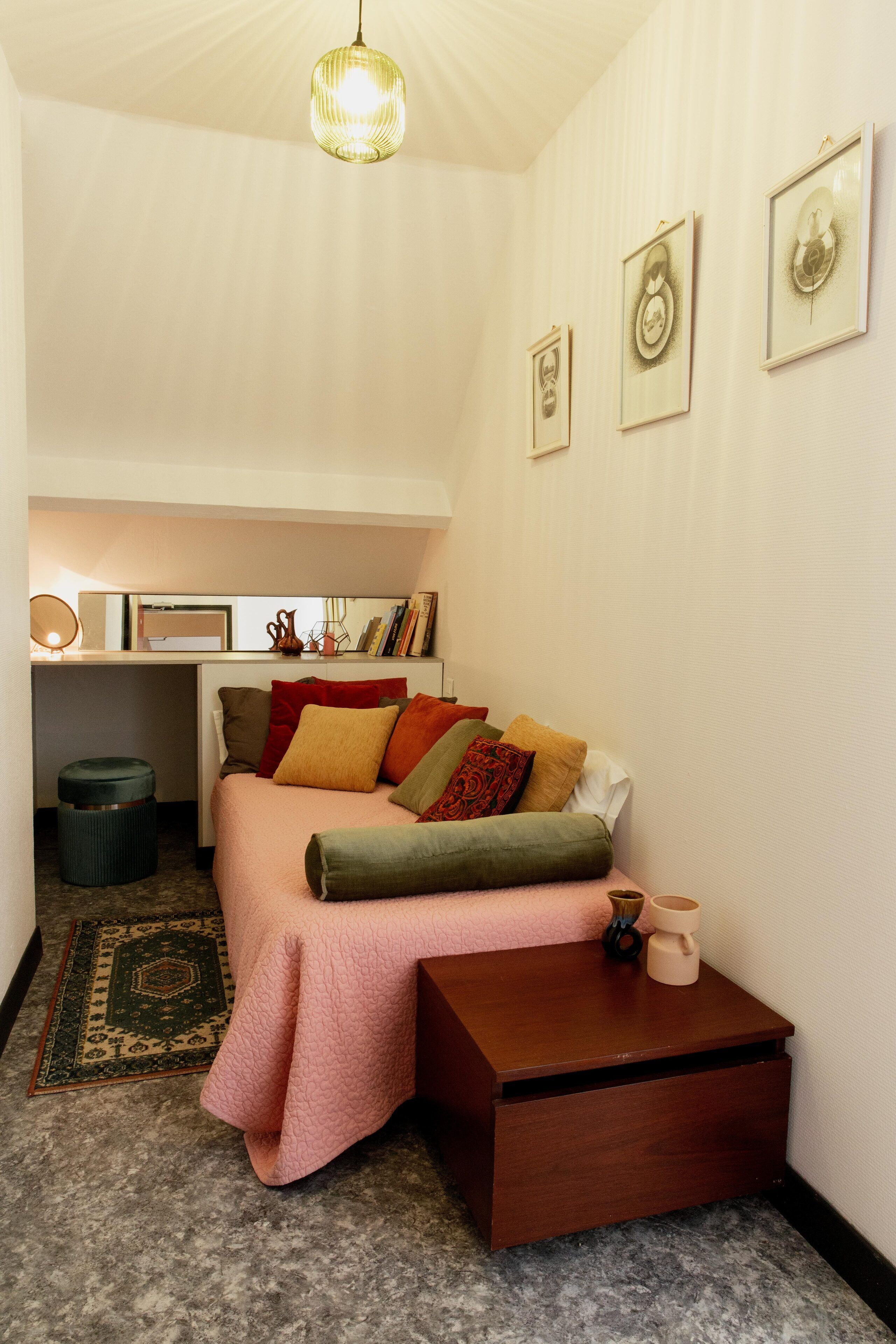 A cozy bedroom with a bed, bedside table, and a desk area.