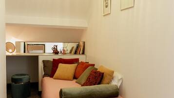 A cozy bedroom with a bed, bedside table, and a desk area.