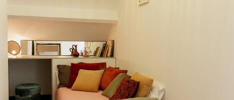 A cozy bedroom with a bed, bedside table, and a desk area.