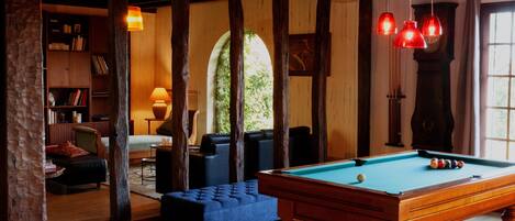 A cozy room with a pool table, comfortable seating, and a bookshelf.