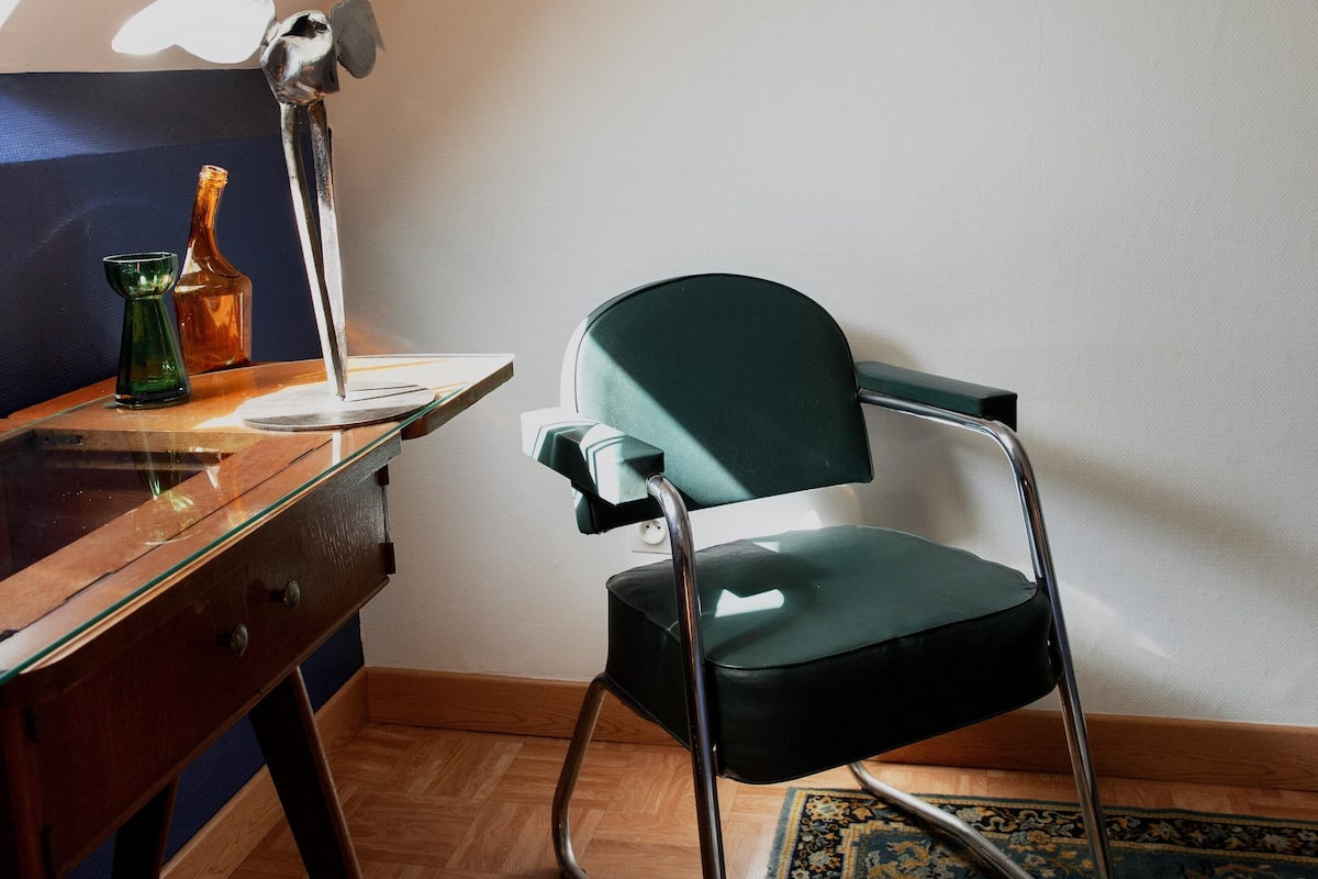 Ein Zimmer mit Schreibtisch, Stuhl und einem Bild an der Wand.