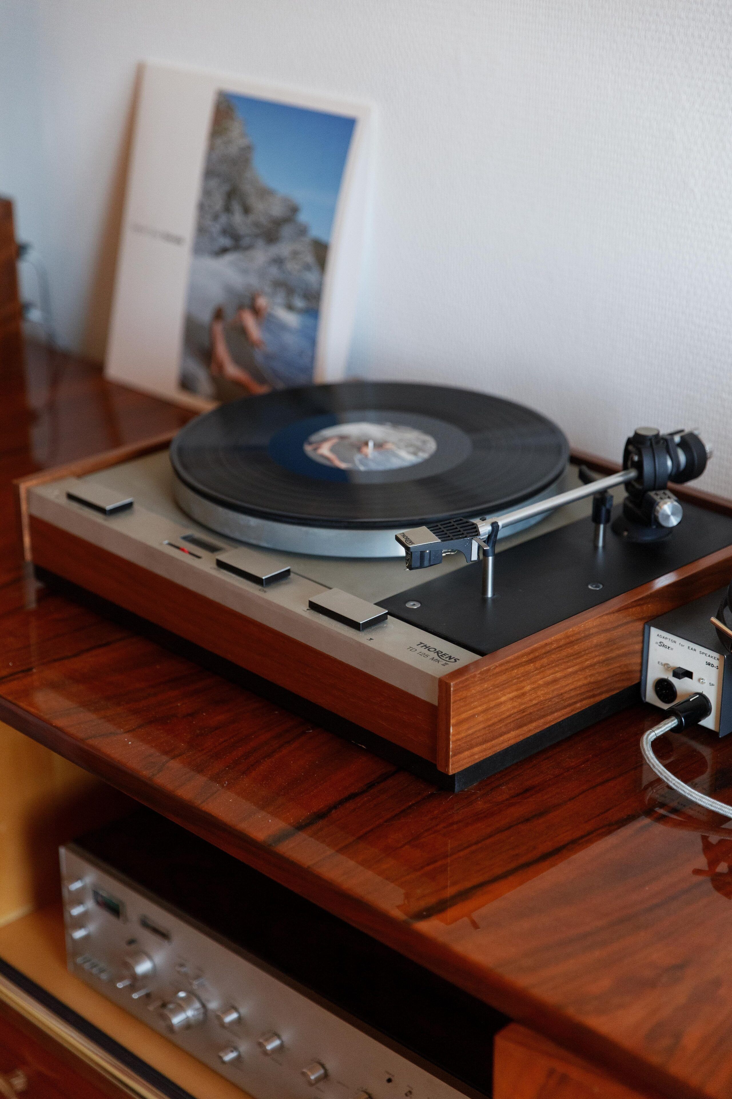 Une platine vinyle posée sur une surface en bois, avec un cadre photo en arrière-plan.