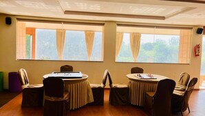 A conference room with two round tables, chairs, and large windows with curtains. - The gorbandh palace (Ankleshwar)