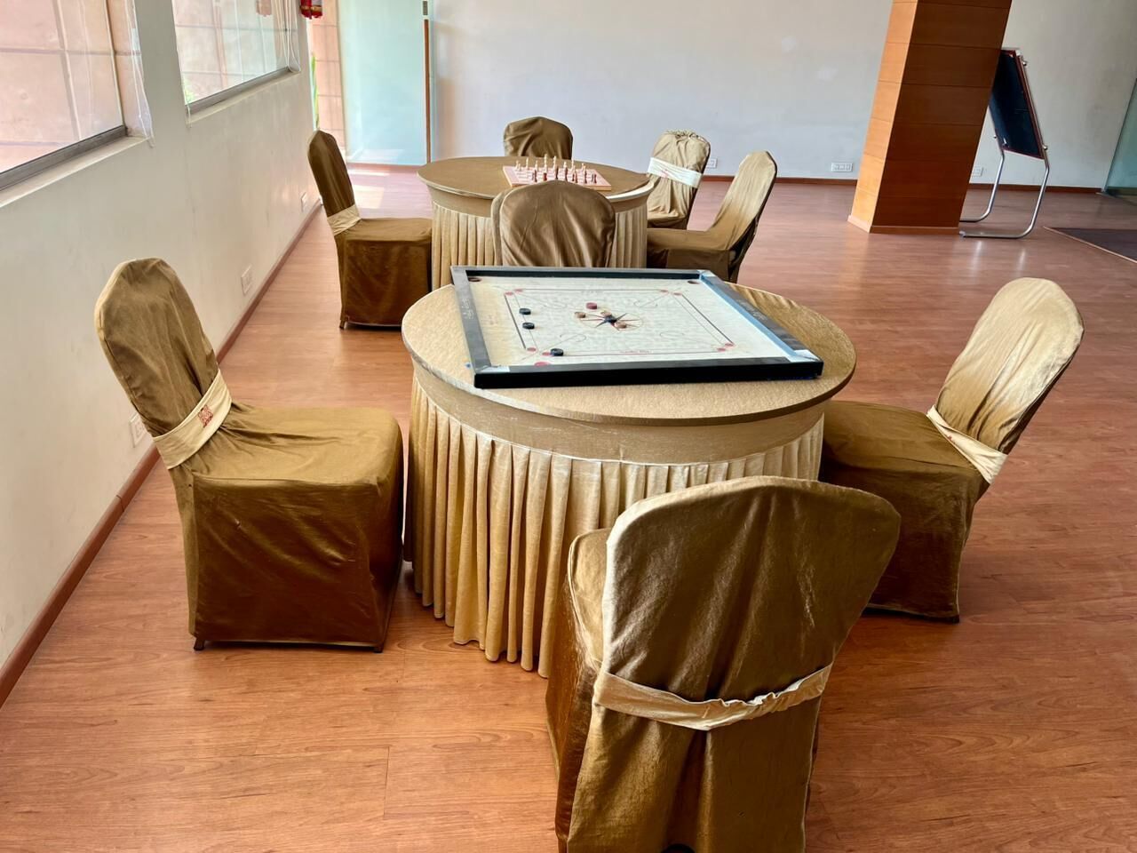 A conference room with a round table and six chairs, each with a beige cover.
