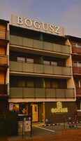 Un edificio de varios pisos con el nombre 'BOGUSZ' visible en la fachada.