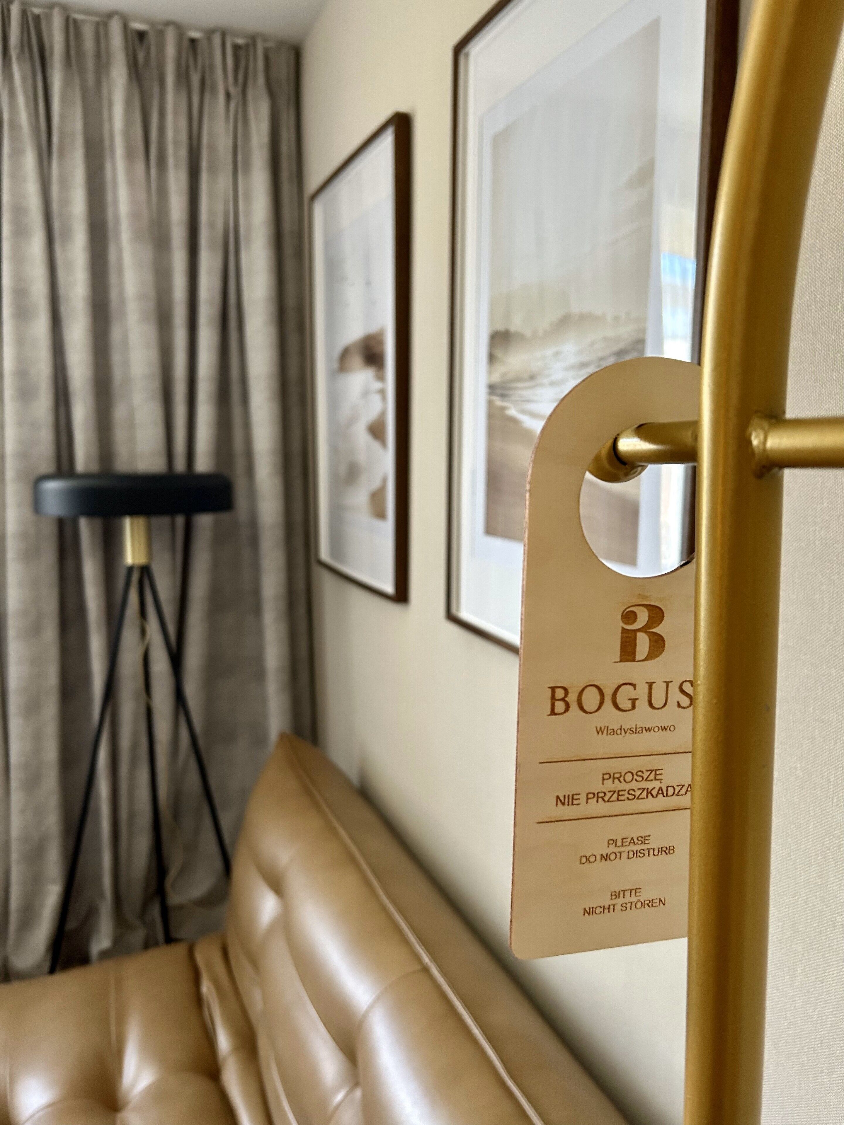 Une pièce avec un canapé en cuir, un lampadaire et des œuvres d’art encadrées accrochées au mur.