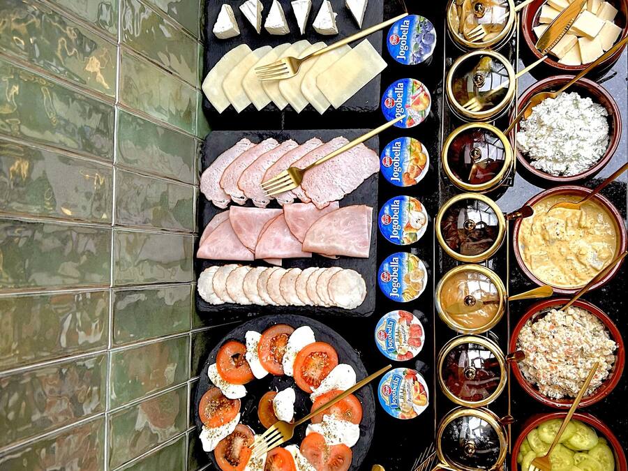 A variety of food items and condiments arranged on a table against a tiled wall.